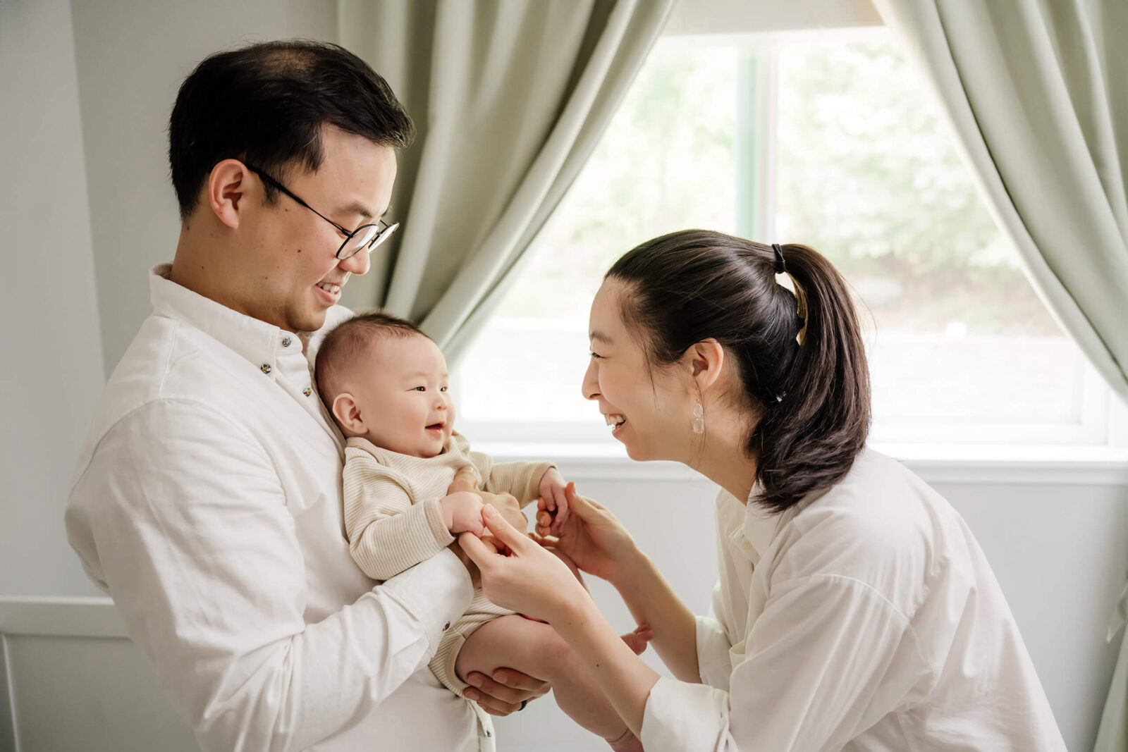 In home newborn photoshoot, parents playing with their son in a nursery